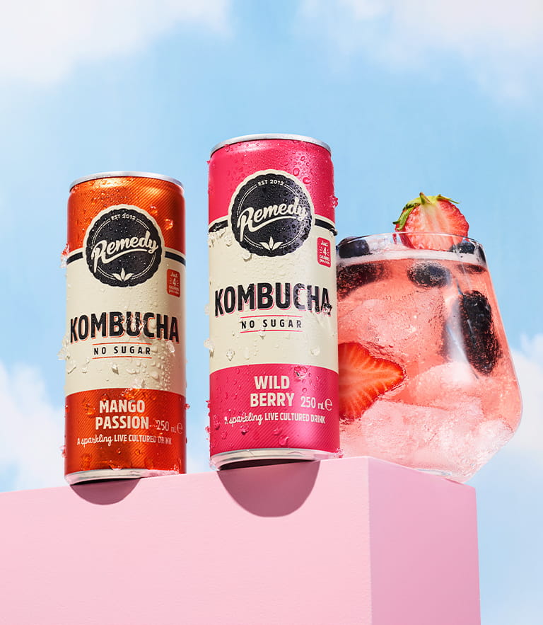 Remedy Kombucha Cans next to glass with ice in it